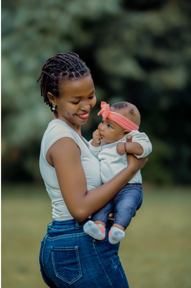 Young African American teen mother smiling as she holds her baby daughter